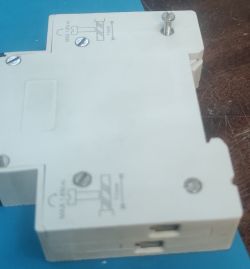 The image shows a white electronic component with several mounting screws placed on a blue surface.