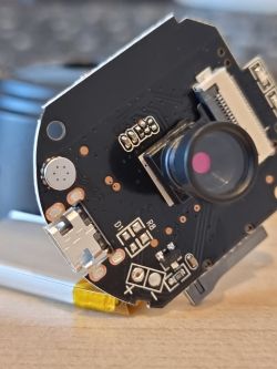 Close-up of the interior of an electronic device featuring a circuit board with a chip and a camera.