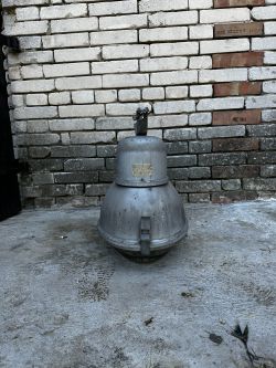 Stara lampa przemysłowa PREDOM-MESKO OURP-250 na tle ceglanego muru.