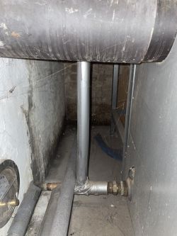 Widok instalacji grzewczej w piwnicy z rurami i zaworami.
