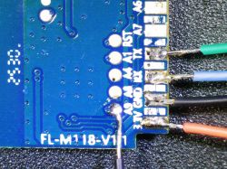 Close-up of blue PCB with colored wires soldered to labeled pins