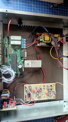 Wnętrze metalowej obudowy z zamontowanymi płytkami elektronicznymi, przewodami i zasilaczem.
