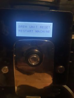 Wyświetlacz ekspresu do kawy z komunikatem o błędzie Brew Unit Reset i Restart Machine.