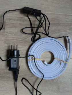 LSC Connect Smart Neon LED Strip with Power Adapter Coiled white LED strip with power adapter and cables.