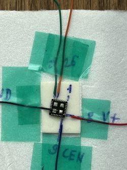 Close-up of a chip with several connected wires placed on a white base.