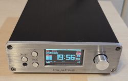 Brushed aluminum device front with 19:56 display, three buttons, and a volume knob