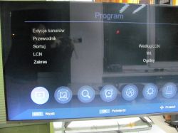 Ekran telewizora z menu ustawień i widocznym odbiciem fotografa.