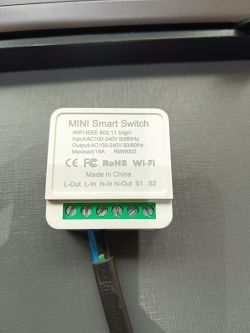 Photo of a mini smart switch with a visible technical label and connected wires.