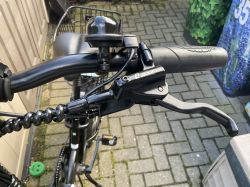 Zbliżenie na zamontowaną klamkę hamulcową Zoom z czujnikiem na rowerze, widoczny dzwonek na kierownicy.