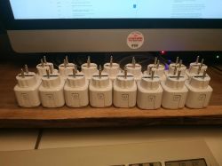 Row of 16 white electrical plugs arranged in front of a monitor.