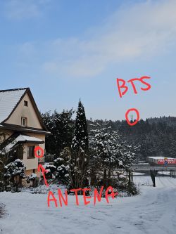 Dom z anteną skierowaną na BTS, zaznaczone czerwonym napisem na zaśnieżonym tle