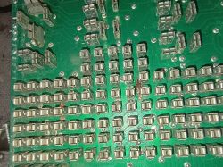 Uszkodzona zielona płytka PCB z licznymi złączami i wypaloną ścieżką