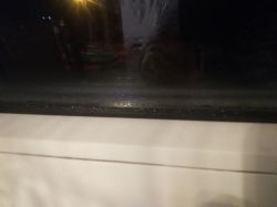Zaparowane szyby okna z widoczną kondensacją wody u dolnej krawędzi.