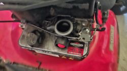 Zbliżenie na gaźnik silnika Briggs &amp;amp; Stratton w kosiarce, z etykietą „PUSH TO PRIME”.