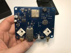 Płytka elektroniczna z układami ESP32, modemami i złączem Ethernet trzymana w dłoni.