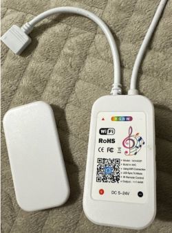 Tuya WX400P RGBW LED controller with info label and two cables on a light surface.