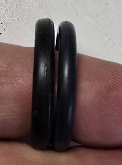 Dwie czarne uszczelki o-ring na palcu, jedna znacznie spłaszczona