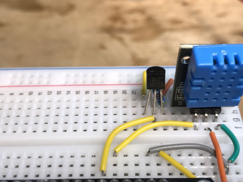 Breadboard with DS18B20 and DHT sensors placed next to each other, connected with colored wires.