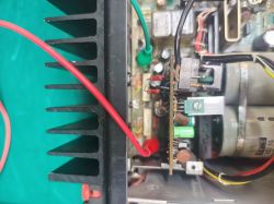 Wnętrze urządzenia: czarny radiator, płytka PCB, przewody i kondensatory elektrolityczne