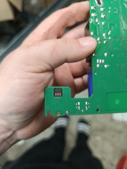 Ręka trzymająca zieloną płytkę elektroniczną z zamontowanym czujnikiem o czterech pinach.