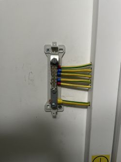 Listwa zaciskowa z przewodami zamontowana pionowo na ścianie.