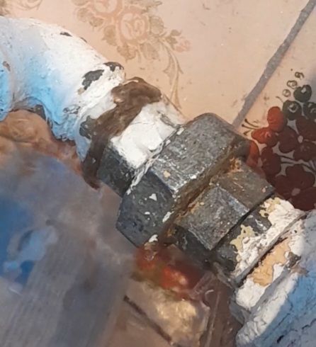 Połączenie grzejnika żeliwnego z widocznym złączem rurowym.