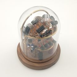 Zegar Nixie w szklanej kopule na drewnianej podstawie z widocznymi elementami elektronicznymi.