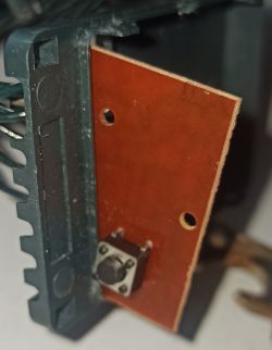 Zbliżenie na płytkę drukowaną z elementem przycisku w plastikowej obudowie.