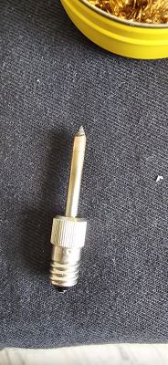 Soldering iron tip on a dark background next to a yellow container.