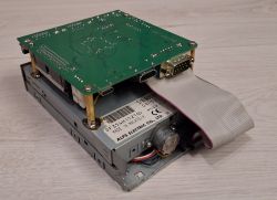 Image of a modified floppy drive with an attached green circuit board mounted on standoffs.