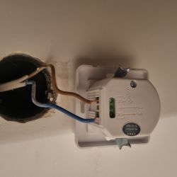 Widok puszki elektrycznej z brązowym i niebieskim przewodem podłączonym do czujnika z oznaczeniem L i N.