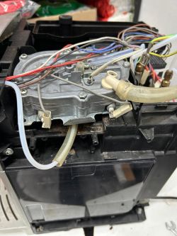 Wnętrze ekspresu do kawy Delonghi z widoczną grzałką i przewodami