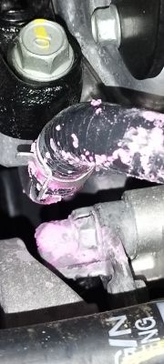 Uszkodzenie na wężu samochodowym z różową substancją.