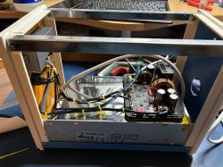 Inside a power supply case: converter module, wiring bundles, and a metal frame on a workbench