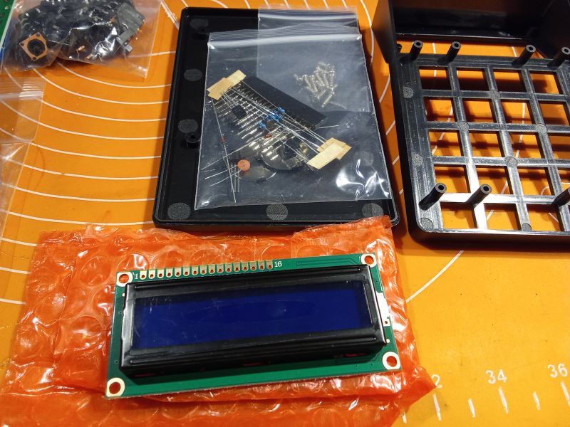Zestaw elementów do składania kalkulatora, w tym wyświetlacz LCD i komponenty elektroniczne.