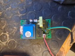 Płytka elektroniki z niebieskim transformatorem i przewodami, sfotografowana z góry na gumowej macie
