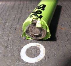 Damaged 18650 lithium-ion cell with torn top and signs of overheating