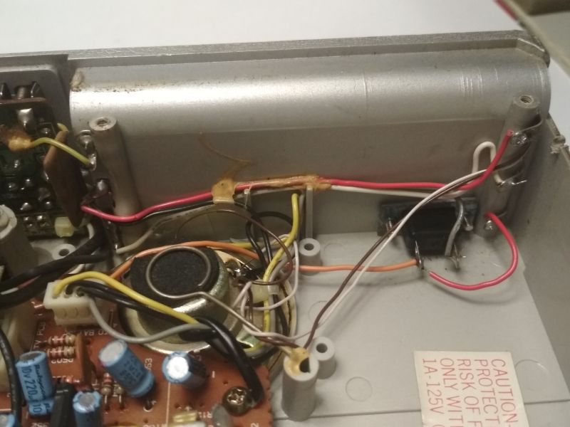 Widok wnętrza starego urządzenia elektronicznego z widocznymi przewodami i komponentami.