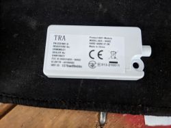 White TRA device: Wi‑Fi module with a label and CE markings on a black surface.