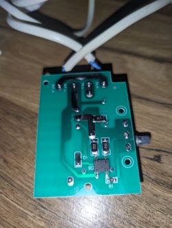 Płytka drukowana z elementami elektronicznymi i podłączonymi przewodami na tle drewnianej powierzchni.