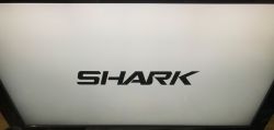 Black SHARK logo on a bright TV screen