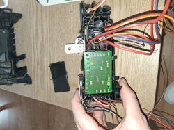 Person holding an electronic component with a circuit board and colorful wires.