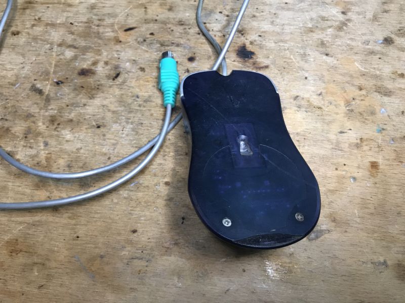 Old Ball Mouse with PS/2 Connection Old ball mouse with PS/2 cable on a wooden surface.
