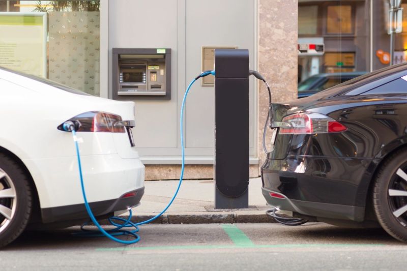 Dwa samochody elektryczne ładujące się na publicznej stacji ładowania