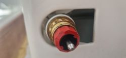 Zbliżenie na zawór termostatyczny grzejnika z czerwoną kryzą ustawioną na N