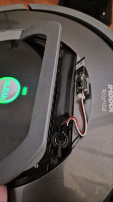 Inside an iRobot Roomba with a small electronic module and wires connected near the compartment