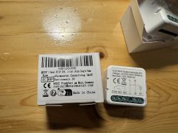 Wi-Fi Switch Module with Box Wi-Fi switch module on a wooden table, next to a labeled manufacturer box.