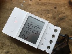 White Sonoff energy meter with an LCD display showing measurements.