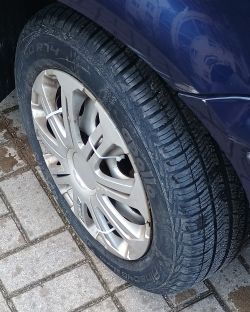 Opona samochodowa marki Apollo Pinceath z felgą na tle niebieskiego nadwozia.
