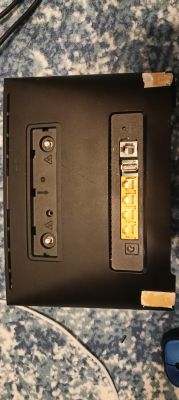 Tył czarnego routera z portami RJ11, USB, czterema LAN i złączami antenowymi, leży na dywanie